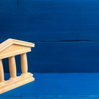 Bank. State Building. wooden government building Judge's hammer and money, on a blue background. concept of state administration and economic institutions. Municipality, government, elections.
